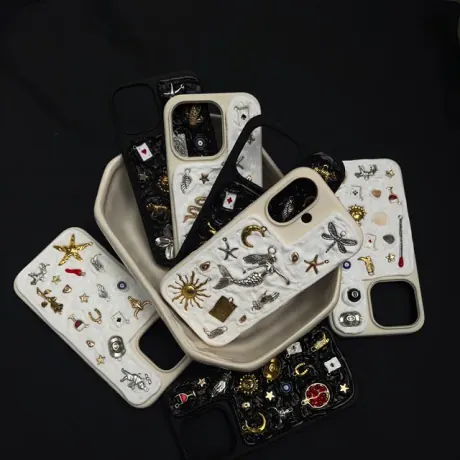 Varias fundas ASTÉRIA blancas y negras llenas de charms